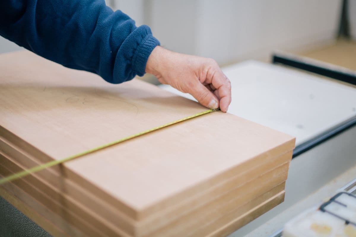 Carpenter measuring wood panels for custom furniture in a Kharghar workshop
