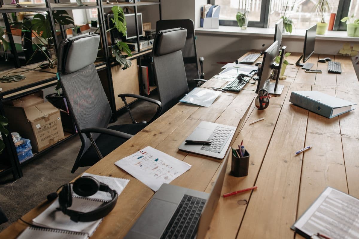 Small office layout in Navi Mumbai with shared wooden desks, chairs and open shelving